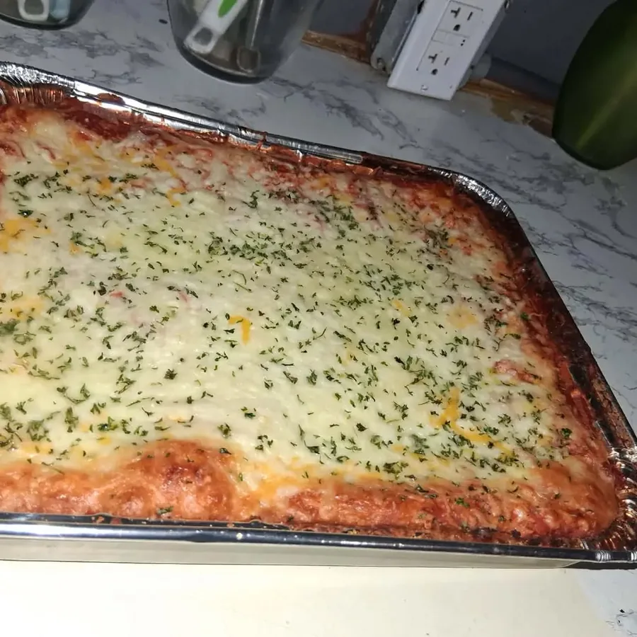 Freshly prepared tray of lasagna topped with melted cheese and herbs